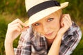 Cute country style. Beautiful young woman in a field while wearing a straw fedora. Royalty Free Stock Photo