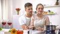 Cute couple cooking meal, romantic date at kitchen, glasses of red wine on table Royalty Free Stock Photo