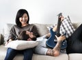 Cute couple on a couch boyfriend playing a guitar music and love concept