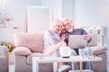 Cute retired couple sitting in room drinking tea and watching comedy