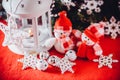 Cute couple of little snowmen is standing near the white fairy lantern with a toy heart on it and decorated fir tree branch. Royalty Free Stock Photo