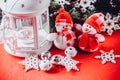 Cute couple of little snowmen is standing near the white fairy lantern with a toy heart on it and decorated fir tree branch. Royalty Free Stock Photo