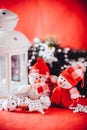 Cute couple of little snowmen is standing near the white fairy lantern with a toy heart on it and decorated fir tree branch. Royalty Free Stock Photo