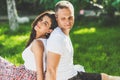 Cute couple in love sitting on a picnic blanket outdoor. Caucasian happy man and smiling brunette woman sitting on green grass Royalty Free Stock Photo