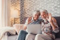 Cute couple of old people sitting on the sofa using laptop together shopping and surfing the net. Two mature people in the living Royalty Free Stock Photo