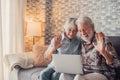 Cute couple of old people sitting on the sofa using laptop together shopping and surfing the net. Two mature people in the living Royalty Free Stock Photo