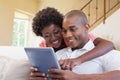 Cute couple relaxing on couch with tablet pc