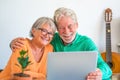 Cute couple of seniors watching movies having fun using laptop at home sitting at the table together. Two mature pensioners Royalty Free Stock Photo