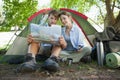 Cute couple sitting by tent reading a map Royalty Free Stock Photo
