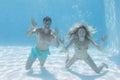 Cute couple smiling at camera underwater in the swimming pool