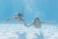 Cute couple smiling at camera underwater in the swimming pool