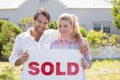 Cute couple standing together in their garden holding sold sign Royalty Free Stock Photo