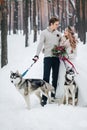Cute couple with two siberian husky are posed on background of snowy forest. Winter wedding. Artwork Royalty Free Stock Photo