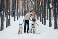 Cute couple with two siberian husky are posed on background of snowy forest. Winter wedding. Artwork Royalty Free Stock Photo