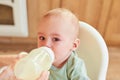 Portrait of a crying baby drinking milk from a baby bottle Royalty Free Stock Photo