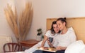 Cute cuddling and snuggling young couple sitting in bed having healthy breakfast with jam toast and coffee