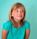 Cute cunning little girl isolated on turquoise background. Human emotion facial expression.