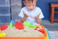 Asian 2 years old toddler boy playing with kinetic sand in sandbox at home Royalty Free Stock Photo