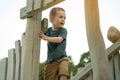 A cute curious toddler boy of two or three years playing on a wooden playground outside. Active games and entertainment for