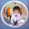 Cute curly baby girl climbing a slide on a playground