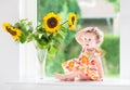 Cute curly baby girl next to sunflower bouquet