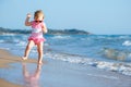 Cute curly baby girl playing on a beautiful tropical beach wearing a cute swimsuit Royalty Free Stock Photo