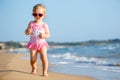 Cute curly baby girl playing on a beautiful tropical beach wearing a cute swimsuit Royalty Free Stock Photo