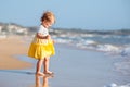 Cute curly baby girlwearing a yellow dress playing on a beautiful tropical beach Royalty Free Stock Photo