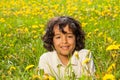 Cute curly boy in dandelions field Royalty Free Stock Photo