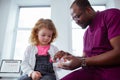 Cute little curly girl taking pills from pleasant pediatrician