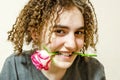 cute curly girl smiles, holding rose in her teeth. Young woman with rose. flirting, congratulations Royalty Free Stock Photo