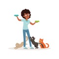 Cute curly-haired girl feeding homeless cats. Volunteer holding bowls with milk. Social help. Teen in glasses, blue t
