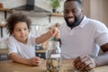 Cute curly-haired kid putting coins into the moneybank Royalty Free Stock Photo