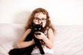 Cute curly little girl kid child in a eyeglasses watching TV with kitty cat best friend at home with remote control in a hands Royalty Free Stock Photo