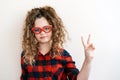 Cute curly long-haired blonde teen girl looks over funny heart-shaped glasses