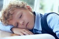 Cute curly tired and exhausted primary school student falling asleep while studying. Royalty Free Stock Photo