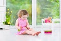 Cute curly toddler girl playing tambourine in a sunny white room Royalty Free Stock Photo