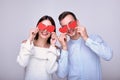 Cute cute girl and mischievous cheerful guy are holding red hearts near their eyes Royalty Free Stock Photo