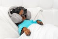 cute dachshund dog in blue pajamas wearing wireless headphones listening and enjoys to music lying in bed at home Royalty Free Stock Photo