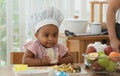 Cute daughter in chef hat drinking fresh smoothie from glass. Little African child girl and mother making healthy fruits smoothie Royalty Free Stock Photo