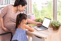 Cute daughter and her pregnant mother using white blank screen laptop at home. Parenthood and technology. Health and medical.