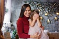 Cute daughter and mother celebrate Christmas. Parent and small child having fun near the Christmas tree indoors, holiday, Royalty Free Stock Photo