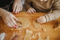 Cute daughter and mother making together christmas cookies on messy table. Adorable toddler girl helper with mom cutting dough for Royalty Free Stock Photo