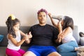 Cute daughters are painting the nails and combing the hair of their handsome young father Royalty Free Stock Photo