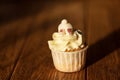 Cute delicious baby cupcake with cheese cream, sugar topping and rabbit paws on wooden table