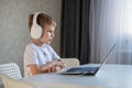 Cute diligent boy is typing on the keyboard and is carefully looking at the laptop screen. Caucasian schoolboy sits at a Royalty Free Stock Photo