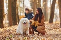 WIth cute dog. Mother with her son is having fun outdoors in the autumn forest Royalty Free Stock Photo