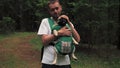 Cute dog pug sitting in the ergo device babycarrier or sling kangaroo carrier