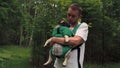 Cute dog pug sitting in the ergo device babycarrier or sling kangaroo carrier