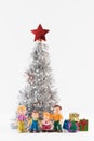 Cute doll family in the background of the lush silver Christmas tree and gift boxes Royalty Free Stock Photo